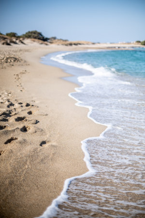 A serene beach with gentle waves and footprints in the sand.の写真素材