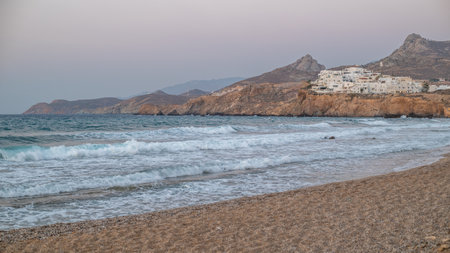 Coastal landscape with waves, rocky cliffs, and white buildings in Naxos, largest of the Greek Cyclades islands in the Aegean sea on 20 August 2023の写真素材