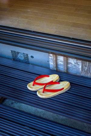Traditional Japanese geta sandals with red straps on wooden steps.の写真素材