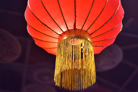 Close-up of a red Chinese lantern with golden tassels.の写真素材
