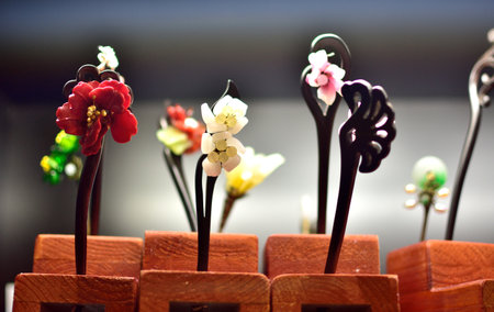 Close-up of decorative hairpins with floral designs displayed in wooden holders.の写真素材