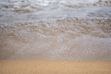 Close-up of gentle waves lapping on a sandy beach.