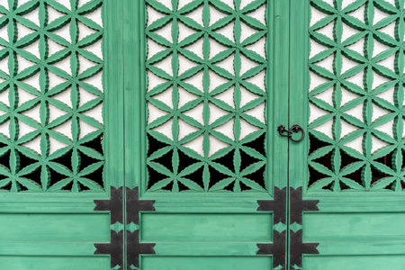 Korean Green wooden door with geometric lattice design and metal handles.の写真素材