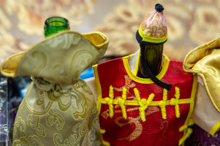 Silk bottle wrappers in shape of decorative figurine in red and gold traditional Chinese costume close-up, colorful craft display with shallow depth of field.の写真素材