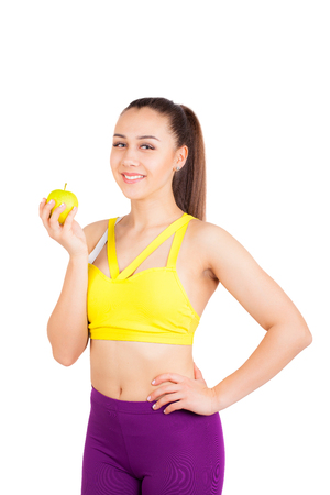 Young and cheerful woman eating a green apple, isolated on whiteの写真素材