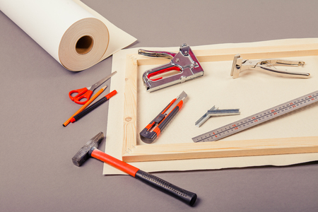 Canvas artist on roll, stretcher for canvas, staple gun and other tools on a gray backgroundの写真素材