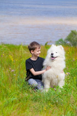 boy in the summer with a large mount dog of the Samoyedの写真素材