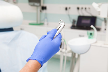 Dental tool for removal of teeth in the hand at the dentist in a blue glove