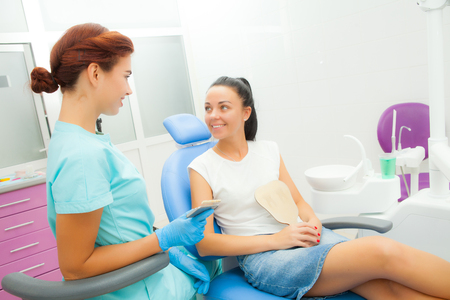 female dentist communicates with a female patient in the treatment room, look at each otherの写真素材