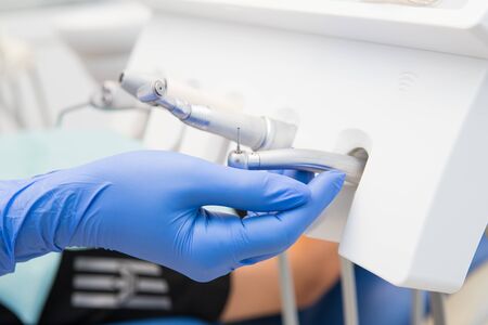 Dentist hand in blue glove taking modern tools for use. Drill with a tipの写真素材