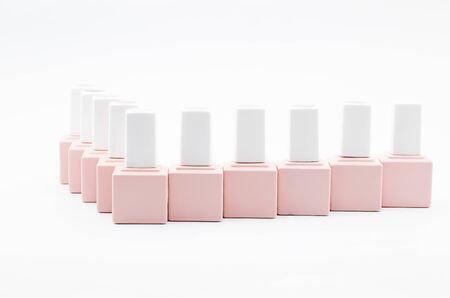 many bottles of nail polish stand in a row. Bottles of pink color on a white backgroundの写真素材