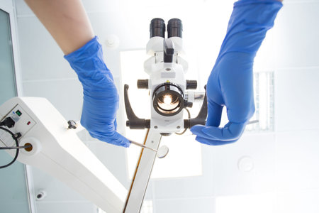 Medical microscope in dentistry, the hands of the dentist in blue gloves in the frame with the tools