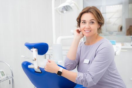 Young beautiful woman dentist smiling while sitting in medical officeの写真素材