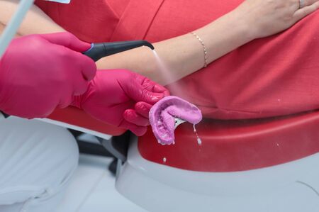 Dentist washes water cast. hands of dentist closeup in red glovesの写真素材