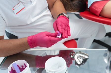 A dentist prepares material for the cast. Close-up dentist in red glovesの写真素材