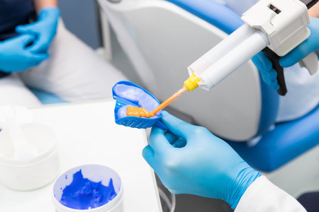Dentist prepares material for a mold of teeth. Close-up of a dentist in blue gloves. Orthopedics in...