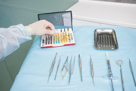The dentists hand takes the endodontic obstructive dental equipment in the dentists office