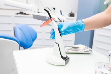 A doctor's hand holding a polymerization UV lamp. Polymerization lamp. Dental UV lamp.の写真素材