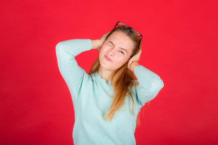 a young teenager girl with hands covering his ears not to hear noise.