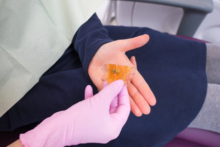 The dentist passes the child an anatomical orthodontic plate made of orange acrylic and metal in the...
