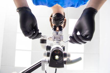 A male dentist is looking into a dental microscope. Bottom view.の写真素材