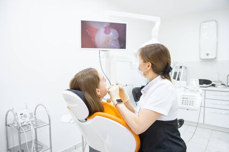 Female dentist diagnoses teeth of patient using intraoral camera in treatment roomの写真素材