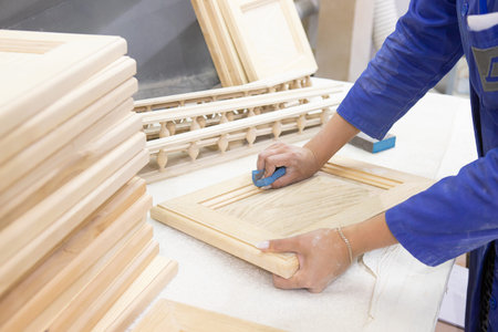 diligent female carpenter sanding wood at the workshop
