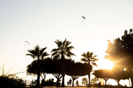 Silhouette of two paragliders in the evening sky with the setting sun.の写真素材