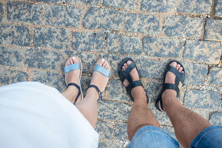Top view of the feet of men and women standing on a stone road in first-person perspective, looking down.の写真素材