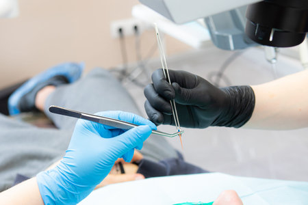 the dentists assistant hands the gutta perchu to the dentist in tweezers. Sterility of instruments...