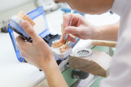 Technician dental is working with complete lower and upper metal ceramic prosthesis dental. Dental...