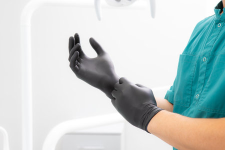 Doctor puts on a black sterilized surgical gloveの写真素材