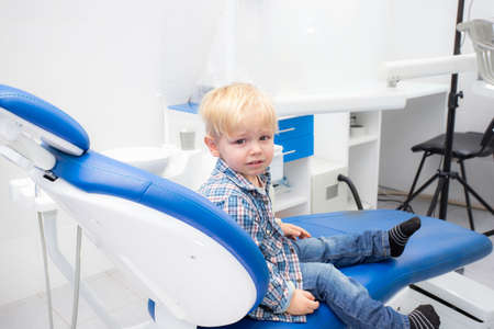 little blond boy is crying in the dentists chair. primary teeth treatmentの写真素材