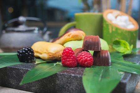 Cream-filled French pastry and chocolates decorated with fresh berries on a wooden tableの写真素材