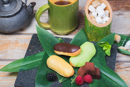 Cream-filled French pastry and chocolates decorated with fresh berries on a wooden tableの写真素材