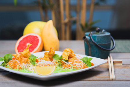Fried breaded shrimp served with lettuce and vegetables on white plate on a table in a restaurantの写真素材