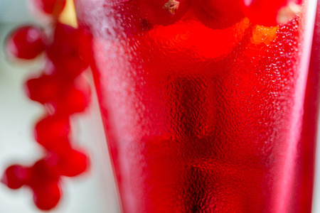 close-up of water droplets on a glasses with alcohol cocktail with cranberry juice on a table in a restaurant with a creative composition and decoration of pieces of orange and fresh berries. soft focusの写真素材