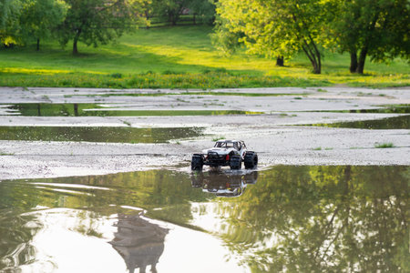 radio controlled monster truck performing a trick at high speed jumps over a large puddle. soft...