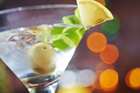one bright delicious glass of cold martinis with olives on a wooden table in a restaurant or bar with creative decoration lime and lemon. soft focus and beautiful bokeh.の写真素材