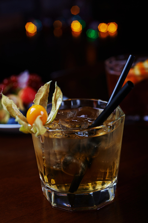 glass of delicious alcoholic cocktails or lemonade with ice and a slice of lemon on a table in a bar or restaurant with a beautiful bokeh in the backgroundの写真素材