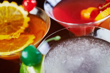 top view of mix bright delicious cocktail with decoration of pieces of orange and a cherry on the table in the restaurant with backgrounds from the disco light. beautiful bokeh and soft focus.の写真素材
