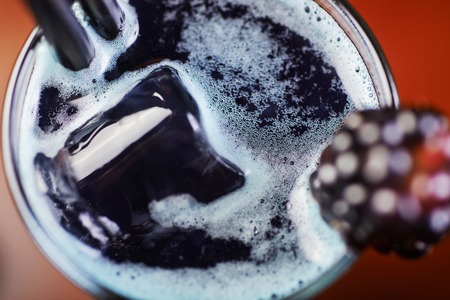 delicious refreshing blackberry alcoholic cocktail or lemonade in a glass on a table in a restaurant with backgrounds of bright disco lights. soft focusの写真素材