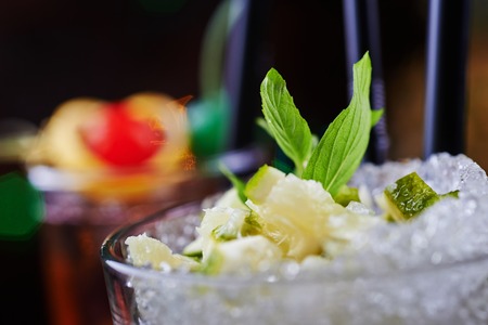 bright delicious refreshing mojito cocktail on a table in the restaurant with the decor of ice and apple sliceswith bright backgrounds of beautiful disco lights. soft focusの写真素材