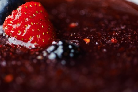 extremely close up glass of tasty tropical alcohol cocktail with berries or lemonade with beautiful decoration on a table in a restaurant with backgrounds of bright colored lights. soft focus.の写真素材