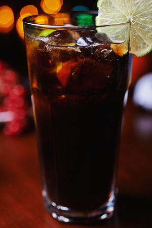 glass of strong alcohol cocktail with orange slices or lemonade with beautiful decoration on a table in a restaurant with backgrounds of bright colored lights. soft focus.の写真素材