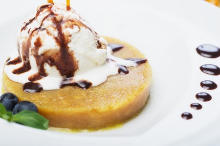 delicious dessert scoop of ice cream on a hot sherbet served on a white plate on a wooden table in a restaurantの写真素材