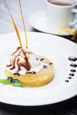 delicious dessert scoop of ice cream on a hot sherbet served on a white plate on a wooden table in a restaurantの写真素材