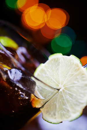 closeup of glass of strong alcohol cocktail with orange slices or lemonade with beautiful decoration on a table in a restaurant with backgrounds of bright colored lights. soft focus.の写真素材