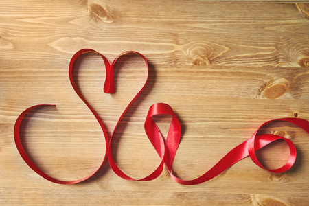 Heart-shaped red ribbon on a wooden table. Creative decoration for Valentine's Day.の写真素材