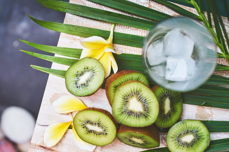 fresh tropical juicy kiwi slices on a wooden table with a tropical decor. soft focus.の写真素材